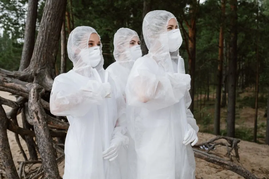 Group of volunteers in white hazmat suits standing in a forest, focusing on environmental conservation.